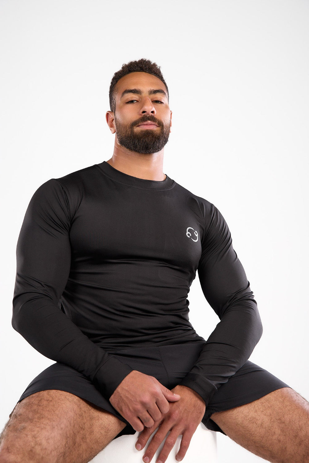 Man wearing a black long-sleeve athletic shirt and shorts on a white background
